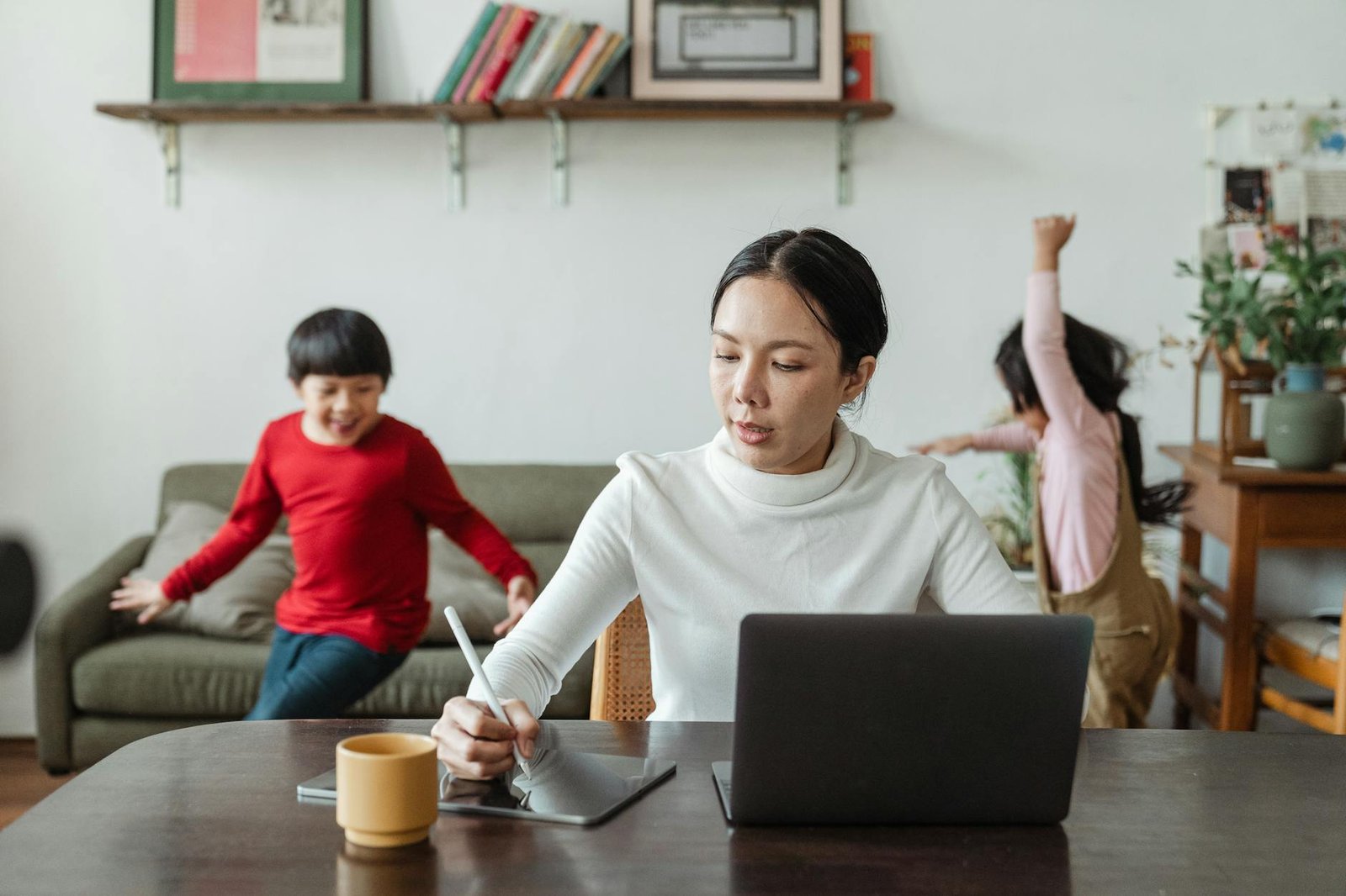Pekerja nyaman di ruang kerja rumah dengan laptop, kopi, dan cahaya alami, menggambarkan kerja remote produktif.